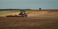 agricultural industrial landscape. a modern tractor with a trailed cultivator works on a hilly field before the autumn sowing Royalty Free Stock Photo