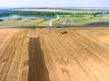 Agricultural land after harvest crop, aerial view at wheat field, farm machinery and green lands Royalty Free Stock Photo