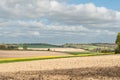 Agricultural landscape farmland with ploughed fields oilseed rape canola growing with bright yellow flowers farmhouse in the