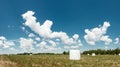 Agricultural landscape with straw packages on field. Cereal bale of hay wrapped in plastic white foil. Hay harvesting, grass