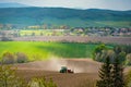 Agricultural landscape with tractor sowing crops in agricultural field in spring. Tractor working on farm land Royalty Free Stock Photo