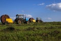 Agricultural machinery, a tractor collecting grass in a field against a blue sky. Hay harvesting, grass harvesting. Season Royalty Free Stock Photo