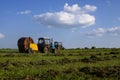 Agricultural machinery, a tractor collecting grass in a field against a blue sky. Hay harvesting, grass harvesting. Season Royalty Free Stock Photo