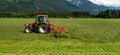 a tractor collecting grass in a field against a blue sky. Season harvesting, grass, agricultural land Royalty Free Stock Photo