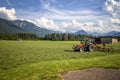 Agricultural machinery, a tractor collecting grass in a field against a blue sky. Royalty Free Stock Photo