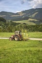 A tractor collecting grass in a field against a blue sky. Season harvesting, grass, agricultural land. Royalty Free Stock Photo