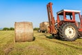 Agricultural scene. Tractor lifting hay bale on barrow. Royalty Free Stock Photo