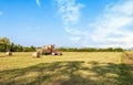 Agricultural scene. Tractor lifting hay bale on barrow. Royalty Free Stock Photo