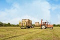 Agricultural scene. Tractor lifting hay bale on barrow. Royalty Free Stock Photo