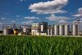 Agricultural Silos on the background of the field. Storage and drying of grains, wheat, corn, soy, sunflower against the blue sky Royalty Free Stock Photo