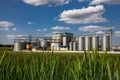 Agricultural Silos on the background of the field. Storage and drying of grains, wheat, corn, soy, sunflower against the blue sky Royalty Free Stock Photo