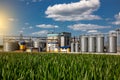 Agricultural Silos on the background of the field. Storage and drying of grains, wheat, corn, soy, sunflower against the blue sky Royalty Free Stock Photo