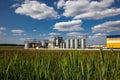 Agricultural Silos on the background of the field. Storage and drying of grains, wheat, corn, soy, sunflower against the blue sky Royalty Free Stock Photo