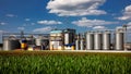 Agricultural Silos on the background of the field. Storage and drying of grains, wheat, corn, soy, sunflower against the blue sky Royalty Free Stock Photo