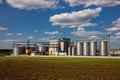 Agricultural Silos. Storage and drying of grains, wheat, corn, soy, sunflower against the blue sky with white clouds.Storage of Royalty Free Stock Photo