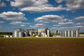 Agricultural Silos. Storage and drying of grains, wheat, corn, soy, sunflower against the blue sky with white clouds.Storage of Royalty Free Stock Photo