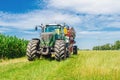 Agricultural summer bright landscape. Large seeder near corn field against a background of clouds