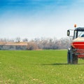 Agricultural tractor fertilizing wheat crop field with NPK Royalty Free Stock Photo