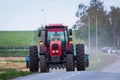 Agricultural tractor moving on the asphalt road after working in field Royalty Free Stock Photo