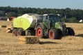 Agricultural tractor pulling an automatic hay baler and baling straw Royalty Free Stock Photo