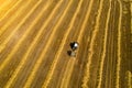 Agricultural work on mowing hay - an old tractor with traces of rust removes earlier hay and forms round wolves of straw. Aerial Royalty Free Stock Photo