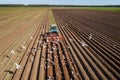 Agricultural work on a tractor farmer sows grain. Hungry birds are flying behind the tractor, and eat grain from the arable land