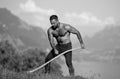 Agriculture, farmer working on alps field. Man farmer works on farm, hay making. Sexy farmer wit hay and scythe