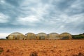 Agriculture and farming background with some weathered greenhouses next to tilled land. Cloudy sky and empty copy space