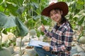 Agriculture industry, farming, people and melon farm concept - happy smiling young woman or farmer with clipboard and melon in