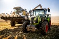 Agriculture industry machinery. Combine harvester and tractor with trailer unloading harvest Royalty Free Stock Photo