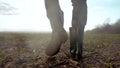 agriculture. man farmer in rubber a boots walk rain along road near a black field. man worker farmer walk rain home