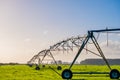 Agriculture modern irrigation. watering spray machine set on the green grassland field with blue sky and warm light scene. I