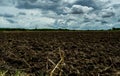 Agriculture plowed field. Black soil plowed field with stormy sky. Dirt soil ground in farm. Tillage soil prepared for planting