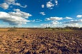 Agriculture plowed field with empty trailer after picking up harvest potato and blue sky with clouds in sunset. Tillage.