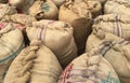 Old jute sacks or bags filled with food grains stored in a warehouse.