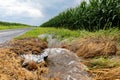 Storm water flowing in ditch between road and farm field. Royalty Free Stock Photo
