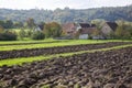 Agriculture scenery with partly ploughed field in front of farm house and barn