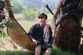 Agriculturist male with loincloth across the shoulder sit relaxing in the basketry crib on nature