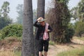 Agriculturist male wear a hat and and his hand on the hat with loincloth across the shoulder near the trunk of sugar palm and