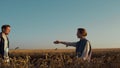 Agro partners shaking hands inspect cultivated wheat harvest in golden sunlight Royalty Free Stock Photo