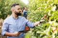 Agronomist inspecting orchard and using tablet, eco organic harvest and modern device