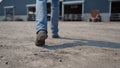 Agronomist legs walking farm yard to barn with cows close up. Agro worker feet.