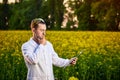 Agronomist man or farmer examine rapeseed oil using tablet on the background of  blossoming rape canola field Royalty Free Stock Photo