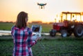 Agronomist using drone in agriculture standing in field in front of tractor Royalty Free Stock Photo