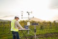 Agronomist using tablet computer collect data with meteorological instrument to measure the wind speed, temperature and humidity