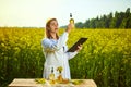 Agronomist woman or farmer examine rapeseed oil using tablet on the background of  blossoming rape canola field Royalty Free Stock Photo