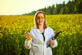 Agronomist woman or farmer examine rapeseed oil using tablet on the background of  blossoming rape canola field Royalty Free Stock Photo