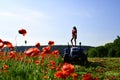 Agronomist woman on tractor, poppy flower.