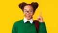 Afro teenager pointing up over yellow studio wall Royalty Free Stock Photo