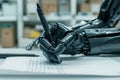 Robot arm holds pen on white paper, workspace background. AI concept art of futuristic writing machine. Close-up view of robotic